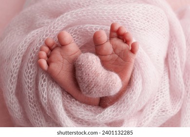 The tiny foot of a newborn baby. Soft feet of a new born in a pink wool blanket. Close up of toes, heels and feet of a newborn. Knitted pink heart in the legs of a baby. Studio macro photography. - Powered by Shutterstock