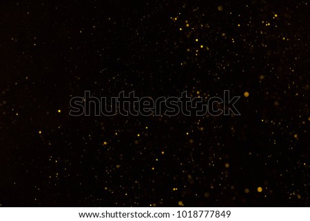 Tiny gold glitter falling on black background