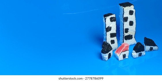 Tiny handmade village model featuring small foam houses with reflections on blue surface creating a creative miniature town photography background and artistic display.