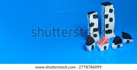 Tiny handmade village model featuring small foam houses with reflections on blue surface creating a creative miniature town photography background and artistic display.