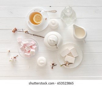 tiny hands holding sweets for tea ceremony in pastel pink and white colors, porcelain, topview