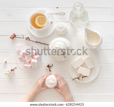 tiny hands holding sweets for tea ceremony in pastel pink and white colors, porcelain, topview
