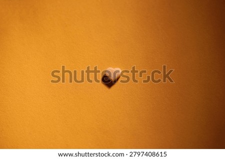 Tiny heart shaped chocolate on matching color background, flat lay
