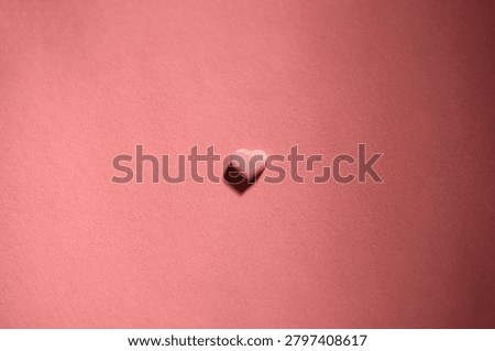 Tiny heart shaped chocolate on matching color background, flat lay