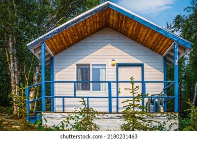 Tiny House In The Woods Of Alaska - Porch With Rails And White Siding  Trimed In Bright Blue