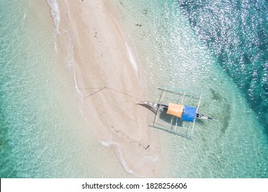 A Tiny Lone Native Wooden Pontoon Boat Is Anchored And Moored Tied To A Small Sandbar Tip Of A Sandbank Shoal That Is Shrinking With The Rising Incoming Ocean Tide In Beautiful Tropical South Pacific
