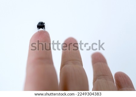 tiny microchip on finger of female hand on white background, research, development of microelectronics and processors, concept future technologies aimed tracking and identifying people, nanotechnology
