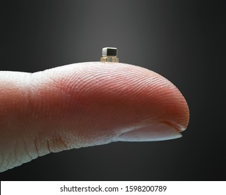 Tiny Microchip On The Fingertip. Finger Holding A Miniaturized Microchip. Technology Concept And Evolution Of Computer Science.