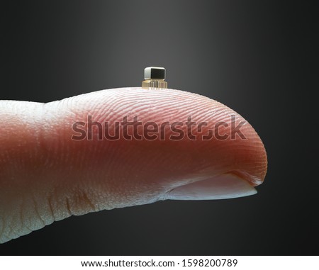 Tiny microchip on the fingertip. Finger holding a miniaturized microchip. Technology concept and evolution of computer science.