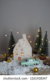 Tiny mint car near white house in christmas tree forest decorated with garlands
