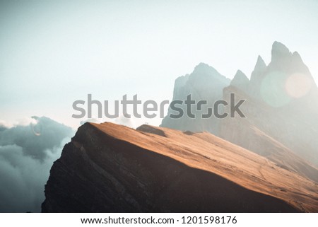 Tiny People against White Clouds during Sunrise mission over Seceda2500m in Val Gardena Italy with Beautiful Sunlight Hitting the Jagged Cliffs
