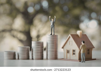 A tiny person stands atop a stack of coins, arms raised in triumph, beside a miniature house and another figure.