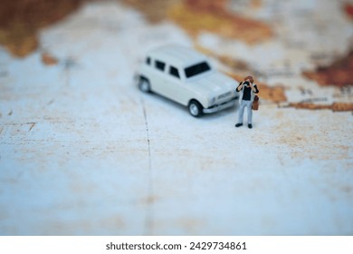 A tiny photographer figure taking a picture of a classic car model on an aged world map background.
 - Powered by Shutterstock