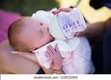 A tiny premature baby girl being fed by bottle by her mother. Not being breast fed due to medical complications.