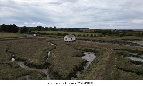 A Tiny Rural House Surrounded By Open Land, Water Trenches And Mud.