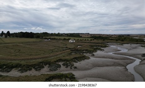 A Tiny Rural House Surrounded By Open Land, Water Trenches And Mud.