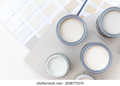 Tiny sample paint cans during house renovation, process of choosing paint for the walls, light grey and pastel colors, color charts and unit samples on background - Shutterstock ID 2038771574
