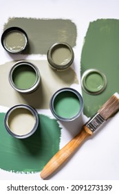 Tiny sample paint cans during house renovation, process of choosing paint for the walls, different green colors, color samples on background