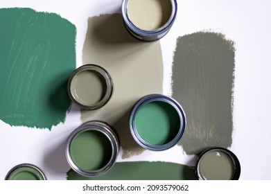 Tiny sample paint cans during house renovation, process of choosing paint for the walls, different green colors, color samples on background