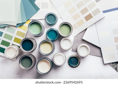Tiny sample paint cans during house renovation, process of choosing paint for the walls, different green and beige colors, color charts on background - Shutterstock ID 2269542695