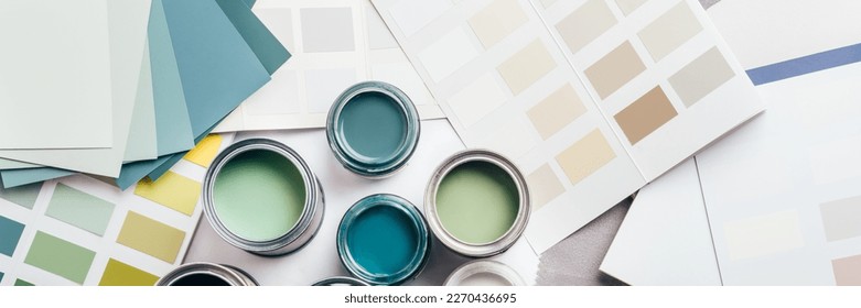 Tiny sample paint cans during house renovation, process of choosing paint for the walls, different green and beige colors, color charts on background, banner size - Powered by Shutterstock