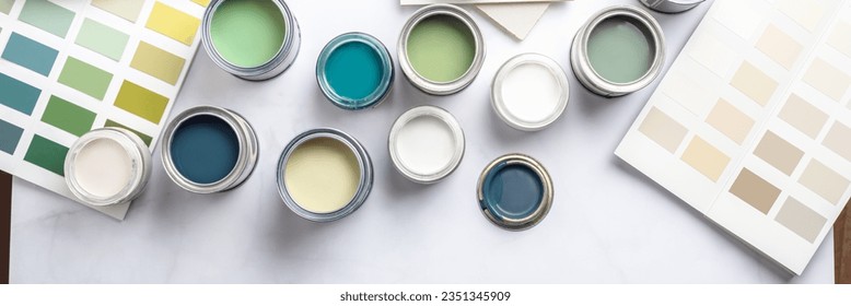 Tiny sample paint cans during house renovation, process of choosing paint for the walls, different green and beige colors, color charts on background, banner size