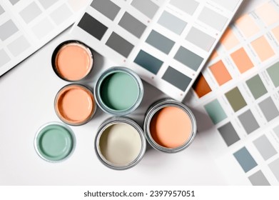 Tiny sample paint cans during house renovation, process of choosing paint for the walls, Peach Fuzz color of the year 2024, color charts on background - Powered by Shutterstock