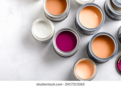 Tiny sample paint cans during house renovation, process of choosing paint for the walls, Peach Fuzz color of the year 2024, color charts on background