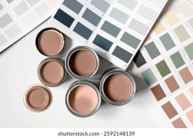 Tiny sample paint cans during house renovation, process of choosing paint for the walls, Mocha Mousse color of the year 2025, color charts on background
