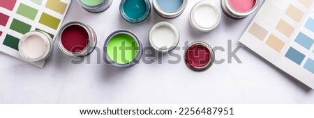 Tiny sample paint cans during house renovation, process of choosing paint for the walls, different colors, color charts on background, banner size