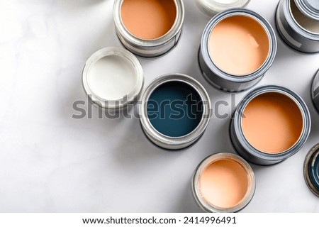 Tiny sample paint cans during house renovation, process of choosing paint for the walls, Peach Fuzz color of the year 2024, color charts on background
