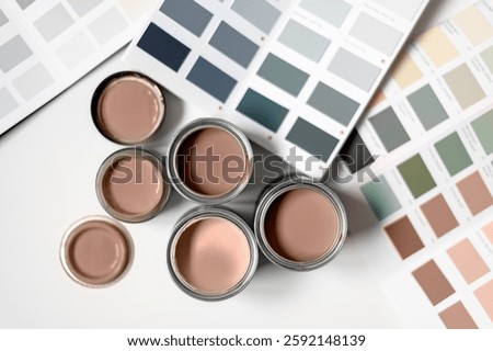 Tiny sample paint cans during house renovation, process of choosing paint for the walls, Mocha Mousse color of the year 2025, color charts on background