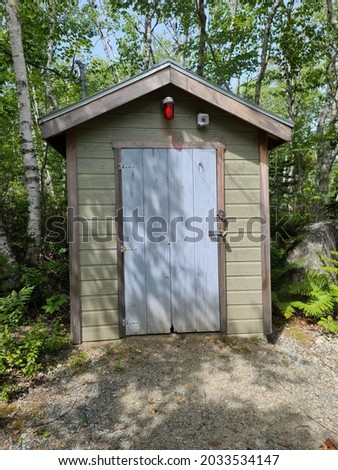A tiny shack with a red light in the center. The shed has heavy duty security system with an alarm, padlock, and a camera.