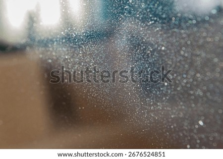 Tiny shimmering particles reflect light on a glass surface, creating an enchanting display. The cozy indoor atmosphere enhances the visual interest and charm of this scene