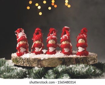 A tiny table Christmas decoration with five figurines of girls in red suits.