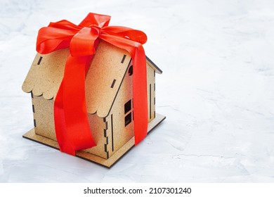 Tiny Toy House Decorated With A Red Ribbon And A Bow. Home Ownership Transfer.