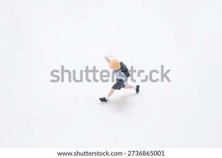 Tiny uniformed figurine strides quickly with backpack swinging