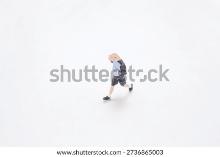 Tiny uniformed figurine strides quickly with backpack swinging