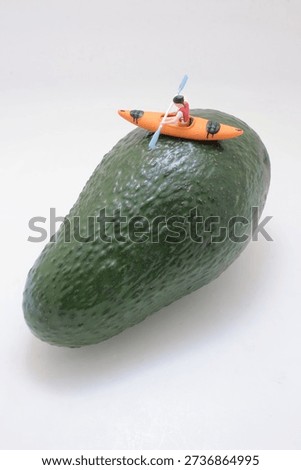 Tiny winter figurine rides board over curved green fruit