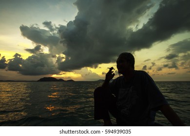 Tioman , Malaysia - April 24, 2015 : An Old Malay Man Smooking On Open Water From The Boat. Beautiful  Sunset In The Background At Tioman Island , Malaysia.