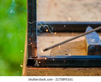 The tip of a hot electrode for electric arc welding. Selective focus. Welding and cutting of metal with an electric welding machine. Sparks and smoke from burning metal.