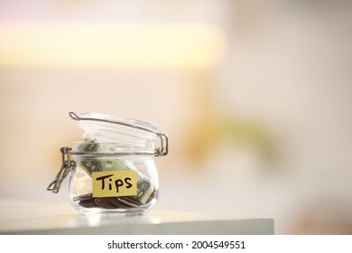 Tip jar with money on table against blurred background, space for text