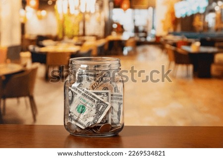 Tip jar in restaurant dining room. Service industry tipping, minimum wage and gratuity concept.