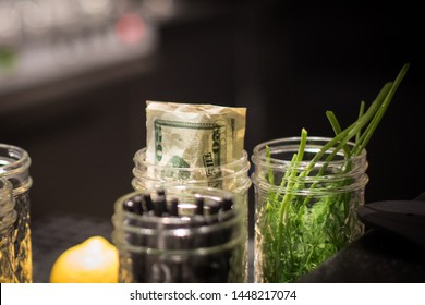 A Tip Jar At An Upscale Bar And Restaurant Is Filled With Multiple 20 US Dollar Bills.