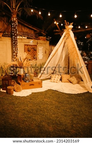 A tipi tent set up in a backyard with wooden decorations