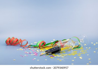 Tipped Over Glass Of Sparkling Wine Against Blue Background, Red Green Streamers And Yellow Confetti Scattered, No Alcohol While Driving, Studio Shot