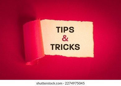 Tips and tricks concept. text appearing behind torn paper in viva magenta, tips and tricks to help you in business, professional advice