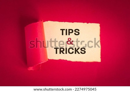 Tips and tricks concept. text appearing behind torn paper in viva magenta, tips and tricks to help you in business, professional advice