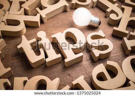 Tips wood word in scattered wood letters with glowing light bulb