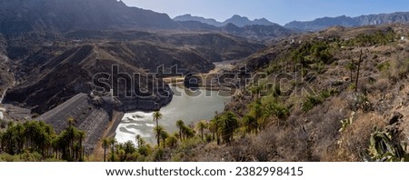 Tirajana Dam also known as Sorrueda Dam, among palm groves of Canarian palm trees. It is part of the World Biosphere Reserve declared by UNESCO. Located in the Tirajana ravine, Gran Canaria, Spain